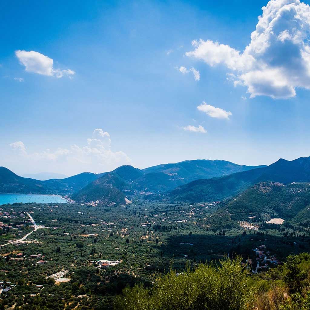 Panoramic view over Nikiana in Lefkada, nestled among green hills, prime for real estate.