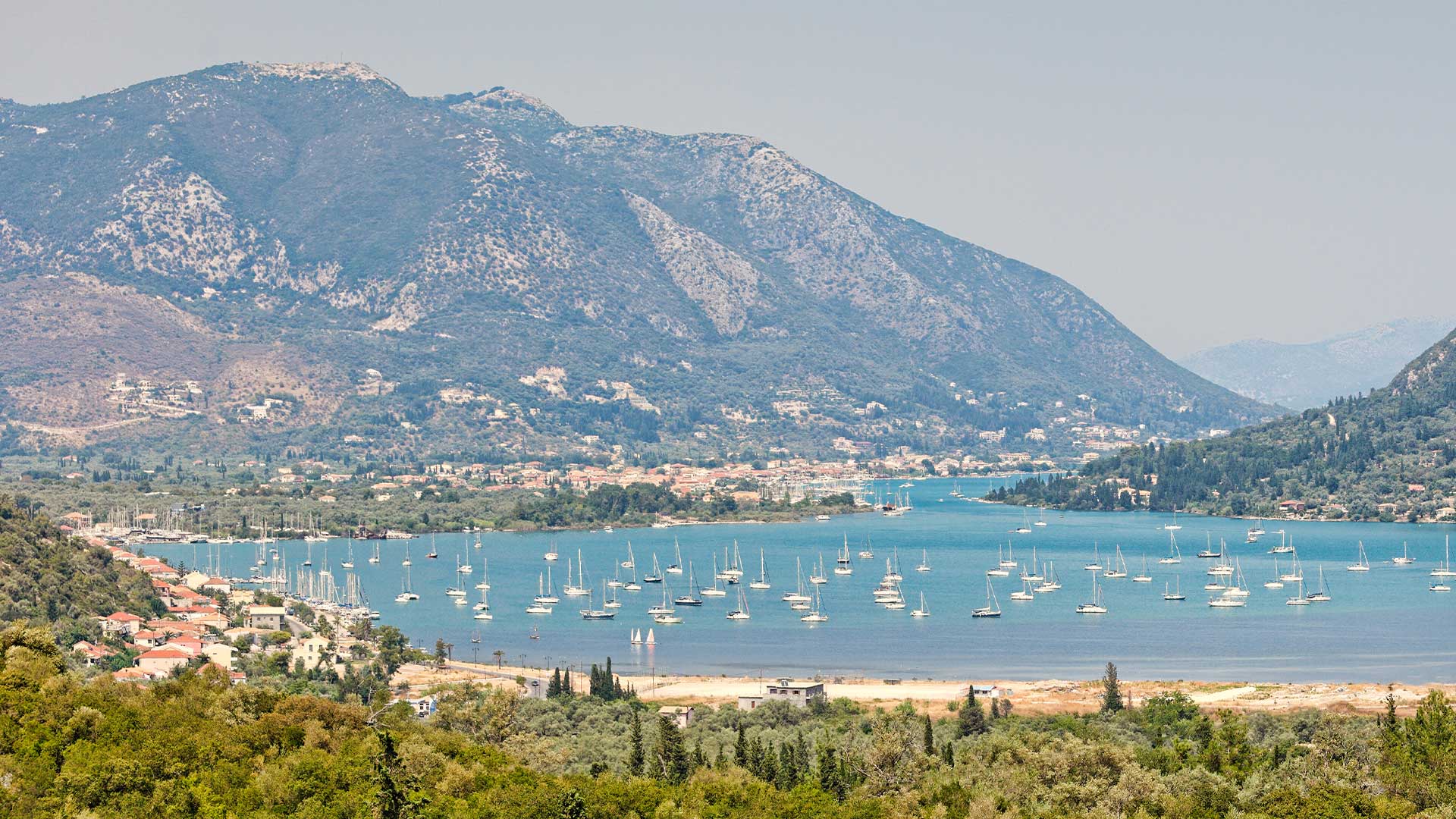 Lefkada Vlycho bay with moored boats, framed by lush hills – prime real estate location.