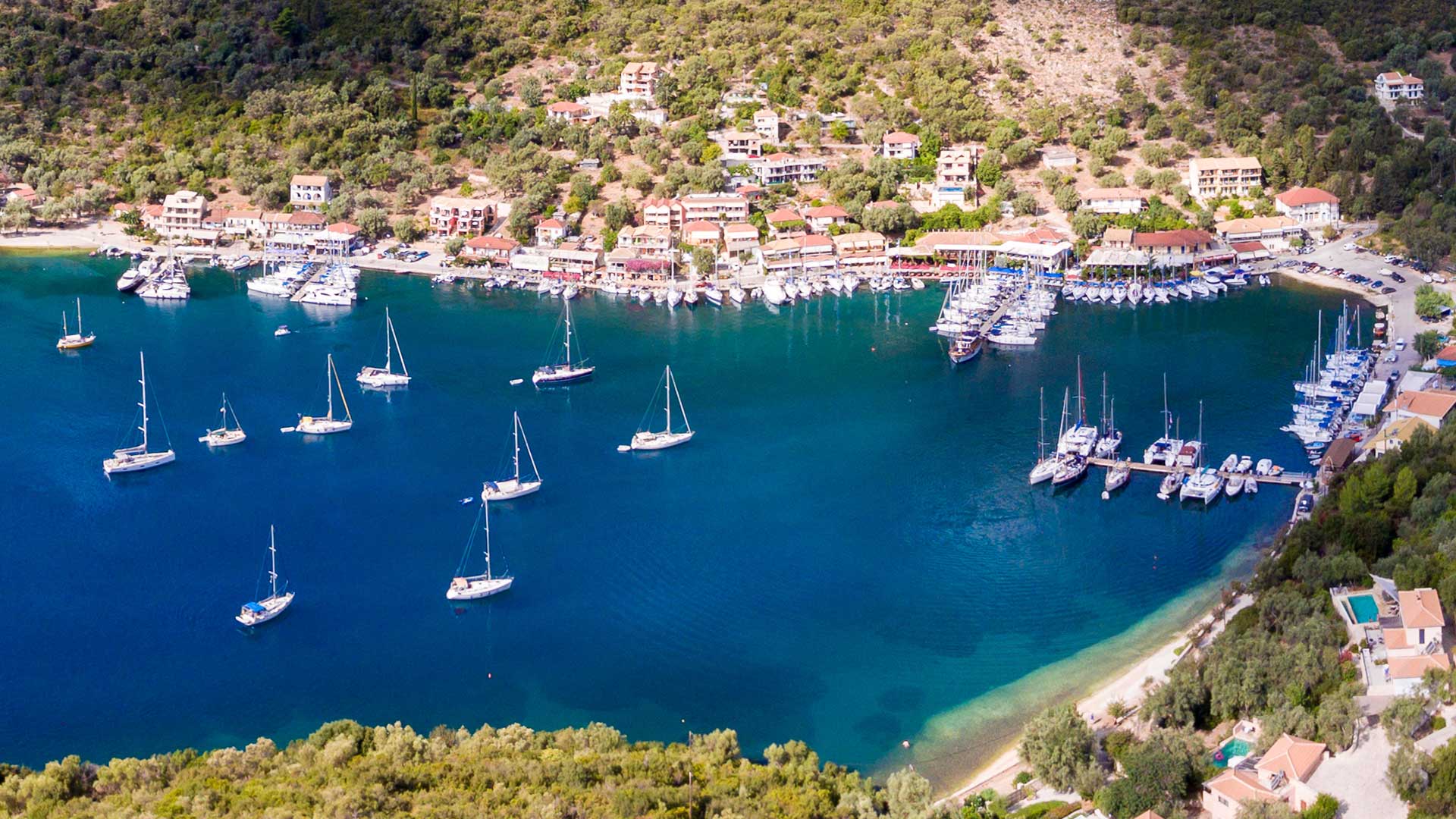 Idyllic view of Syvota Bay in Lefkada, dotted with yachts and surrounded by lush real estate.